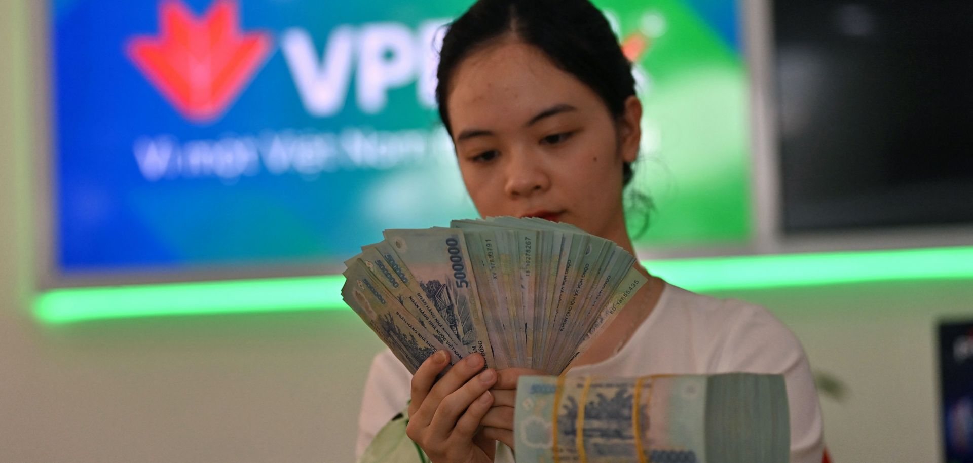 A bank employee checks currency notes at a branch of VPBank in Hanoi, Vietnam, on June 29, 2023, after authorities announced the country's economic growth had slowed in the first half of the year. 