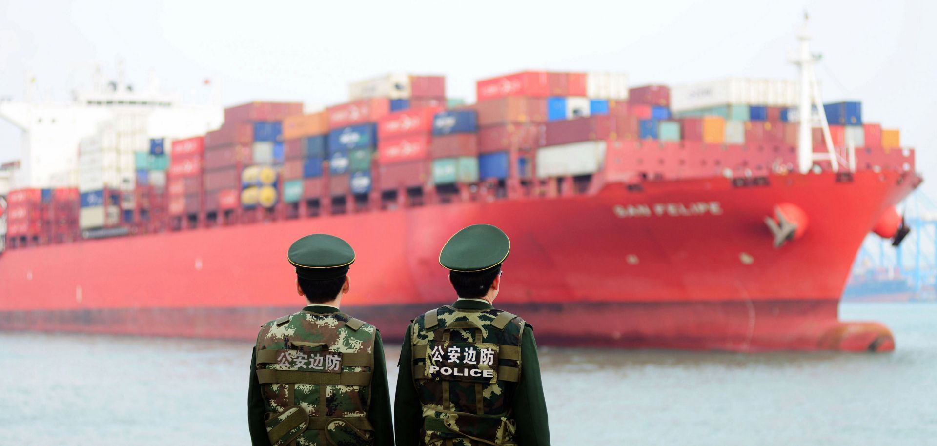 Chinese police officers watch a cargo ship in Qingdao, a seaport in Shandong province, on March 8, 2018.