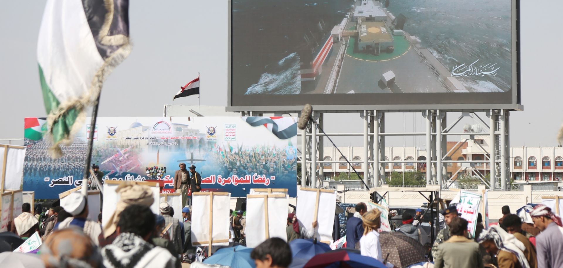 Yemenis stand under a billboard depicting the seizure of an Israeli-linked ship in the sea by Yemen's Houthi-run coast guards during a demonstration staged in solidarity with the people of Gaza and against U.S. President Donald Trump's deal to end the Israel-Hamas war on Oct. 3, 2025, in Sanaa, Yemen. 