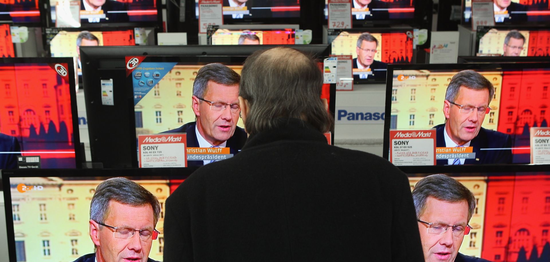 A shopper stops to watch the news in the window of an electronics store.