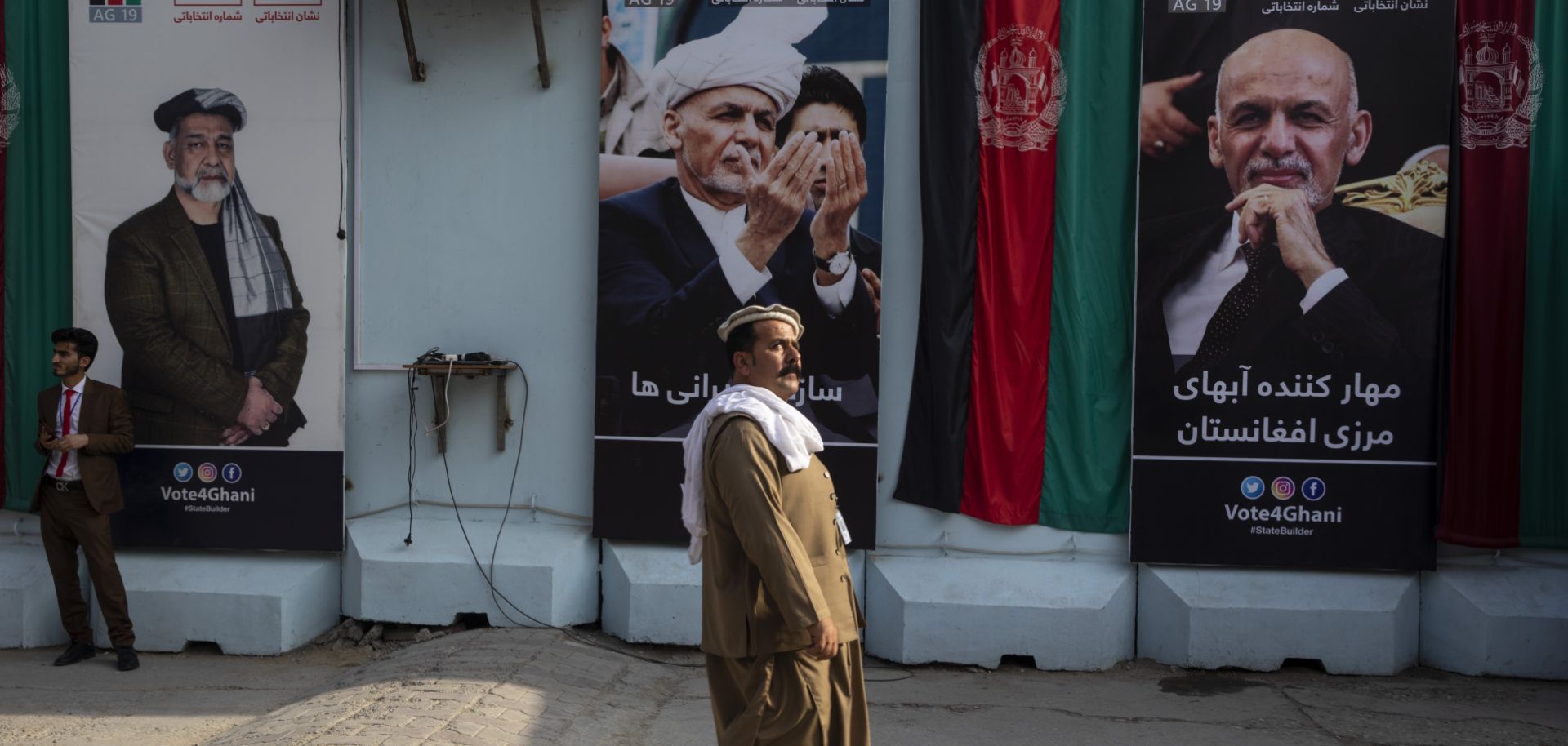 A man walks by election billboards outside of Afghan President Ashraf Ghani's campaign headquarters in Kabul on Sept. 29.