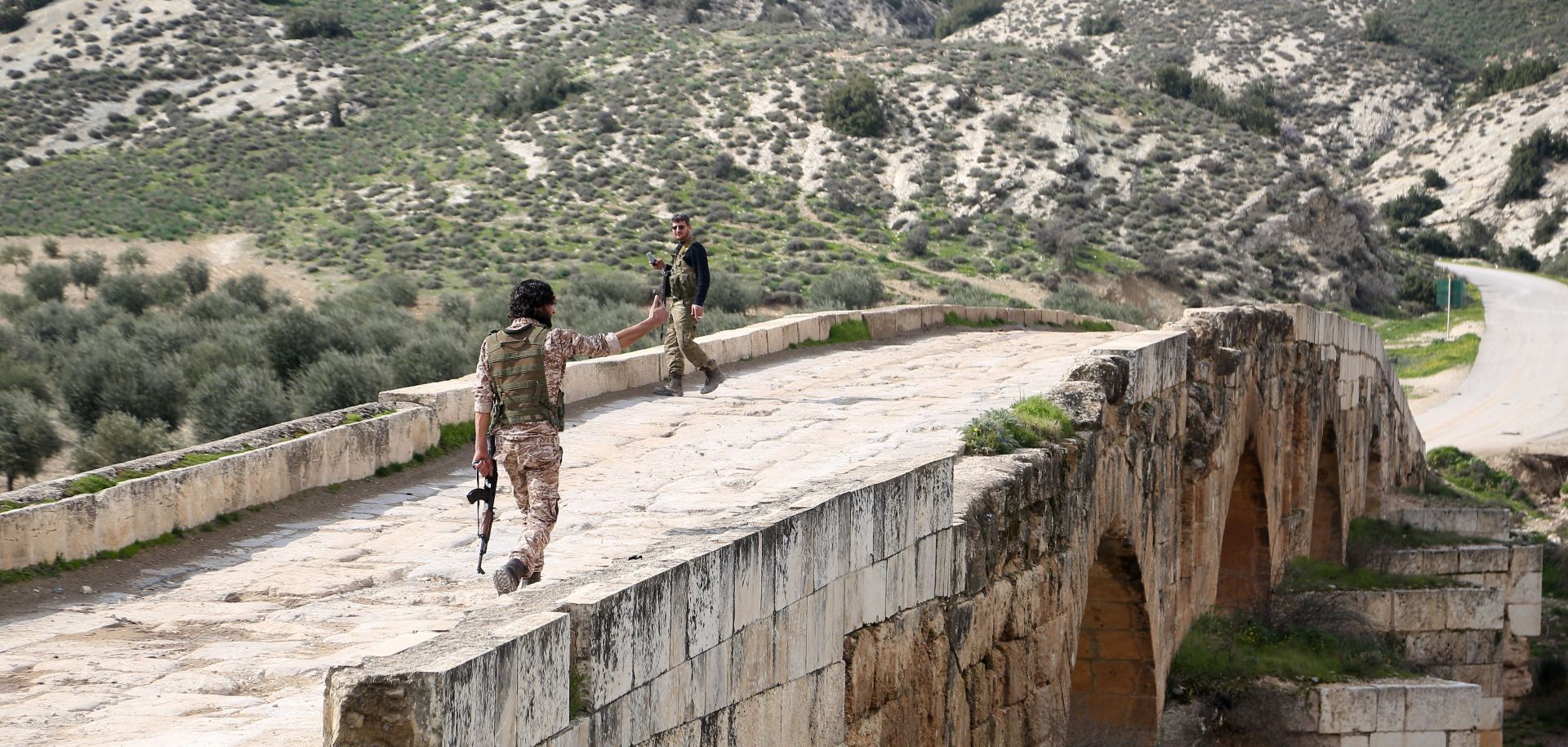Turkish-backed Syrian opposition fighters walk on the Roman bridge in the archaeological site of Cyrrhus, northeast of the Syrian city of Afrin, in February 2018.