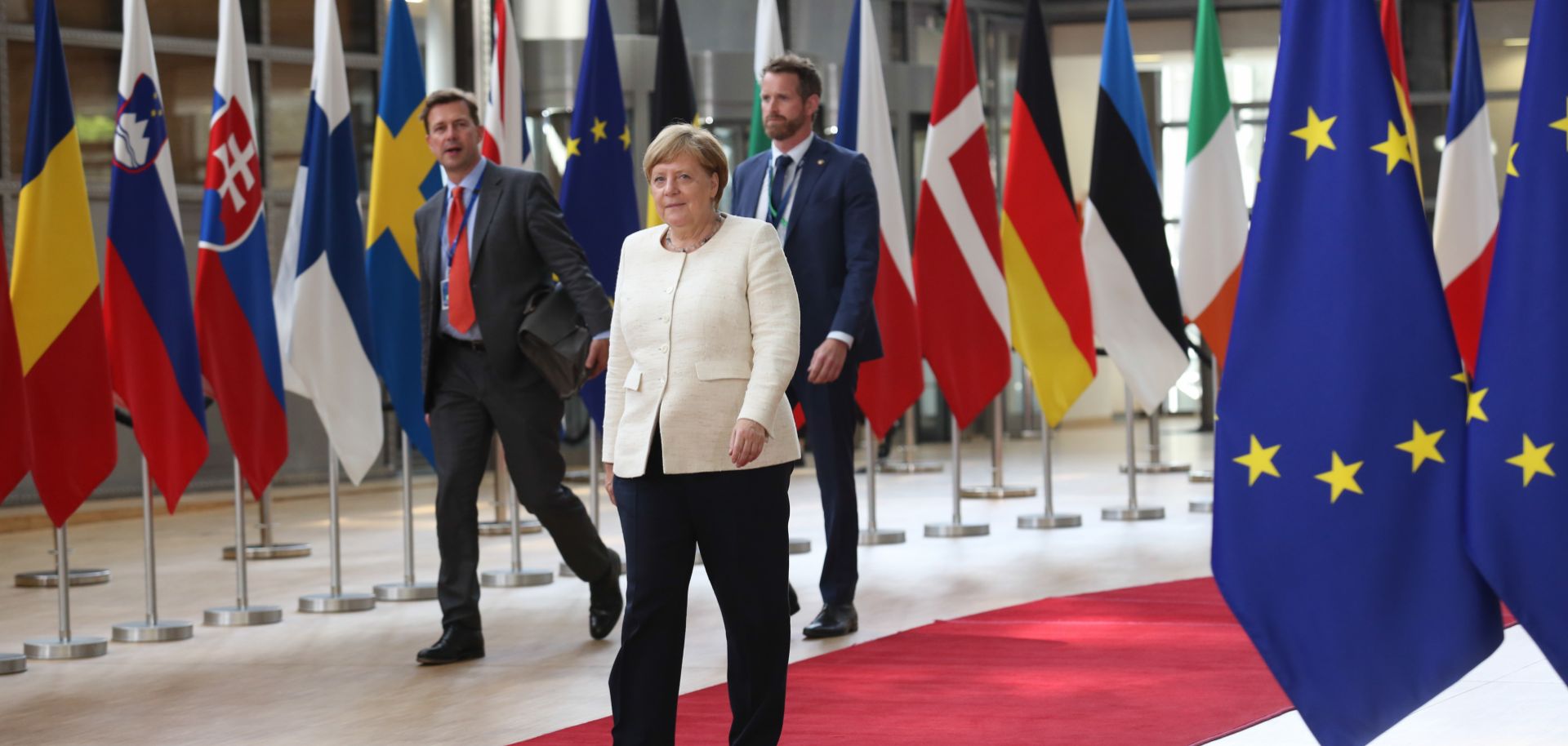 Angela Merkel walks down a red carpet lined with flags as she arrives at the Europa Building in Brussels, Belgium.