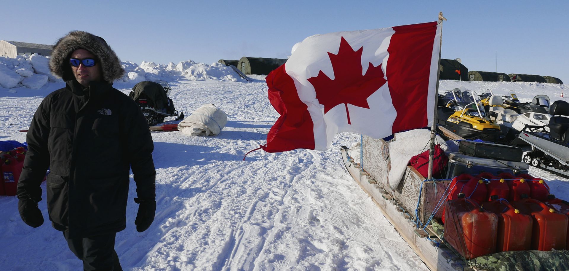 A project manager for the Arctic Research Foundation on April 9, 2015, walks past snowmobiles used by Canadian troops deployed to the territory of Nunavut to demonstrate Canadian sovereignty in the Arctic.