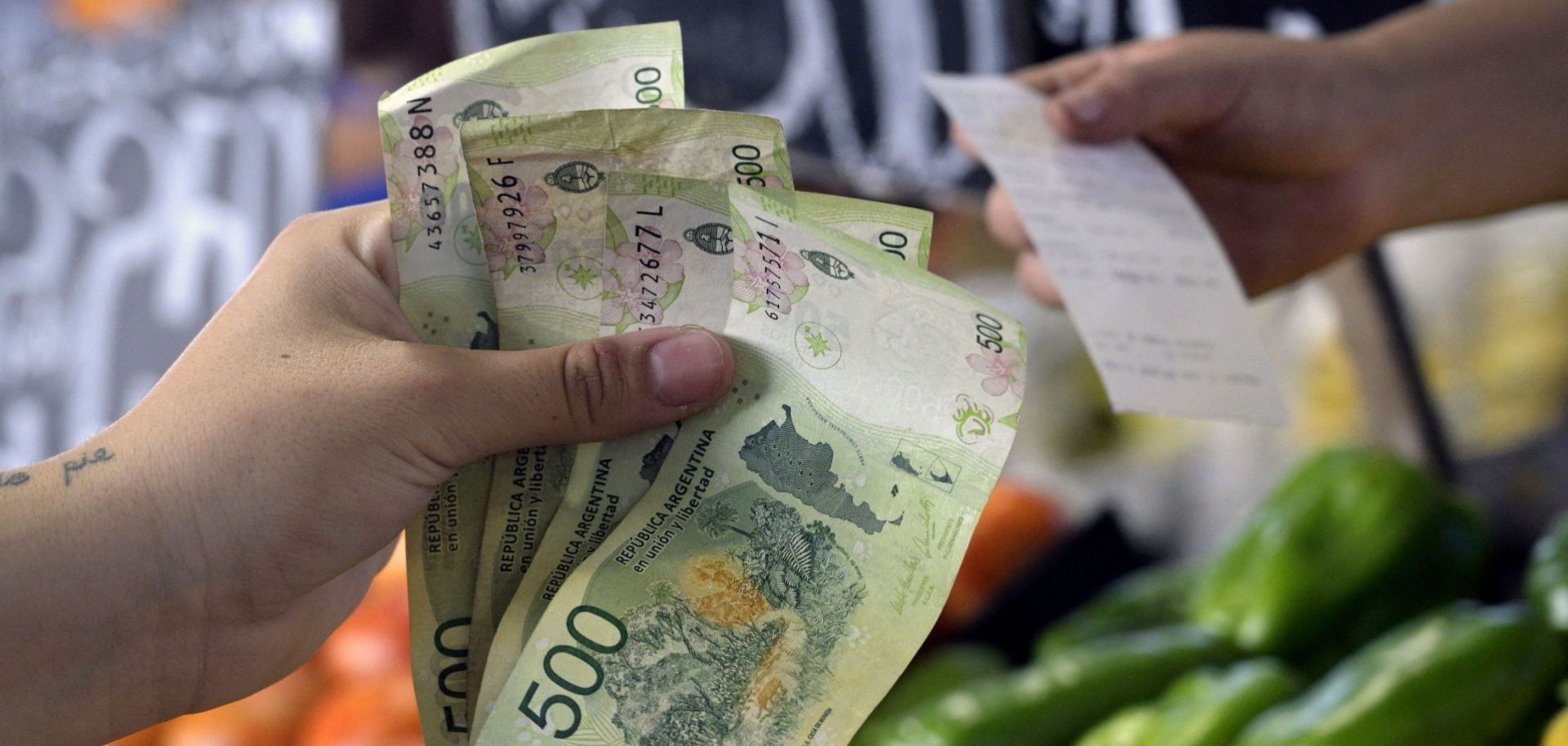 A woman pays for fruits and vegetables in Argentine pesos at a market in Buenos Aires on Feb. 10, 2023.