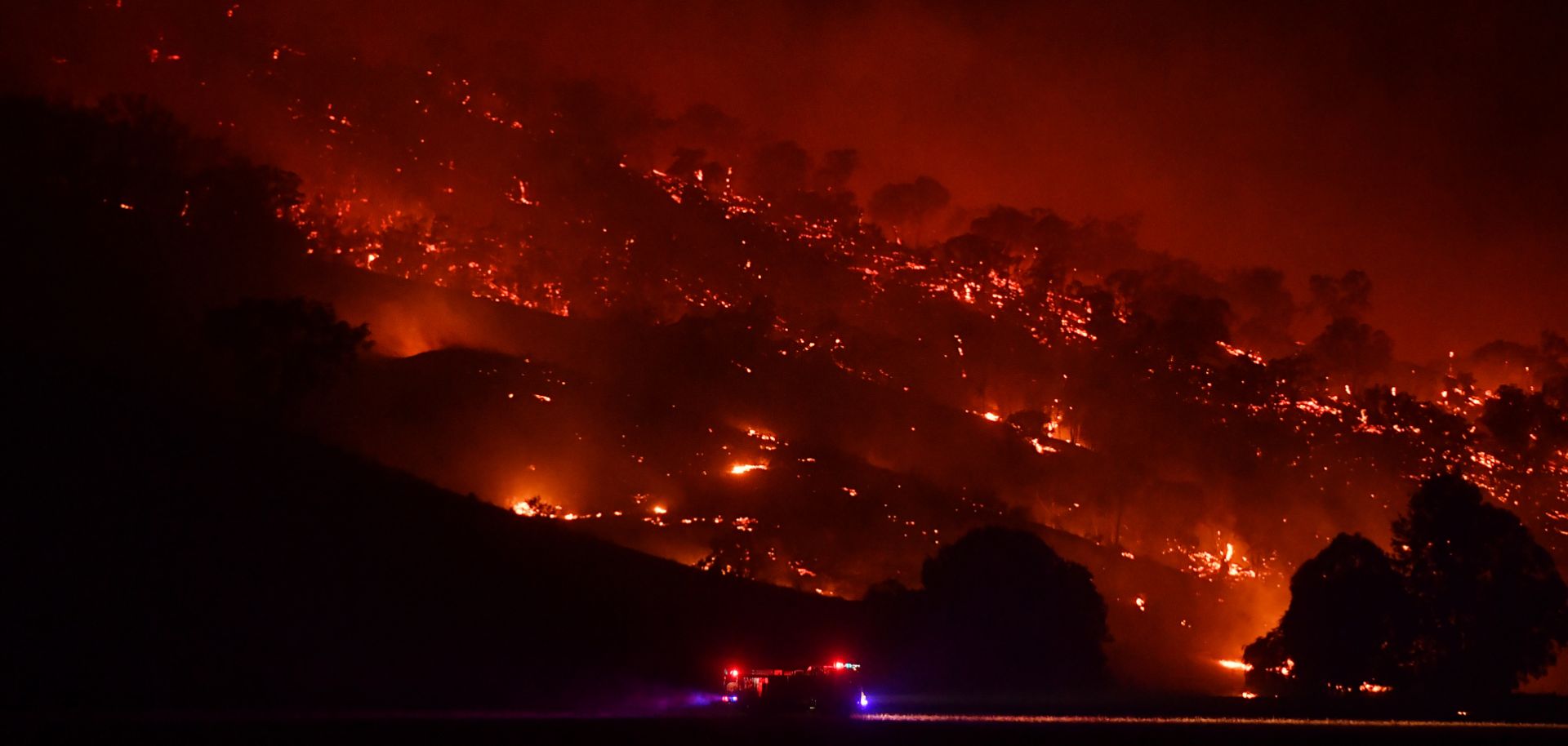 A fire truck drives past a hill engulfed in flames on the night of Jan. 20, 2020 in Mount Adrah, Australia. The 2020 fire season has hit the southern coast of New South Wales particularly hard.