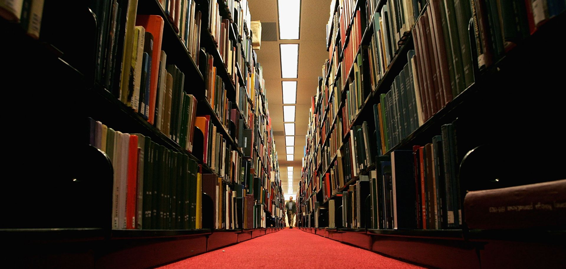 A man walks down a corridor in a library.