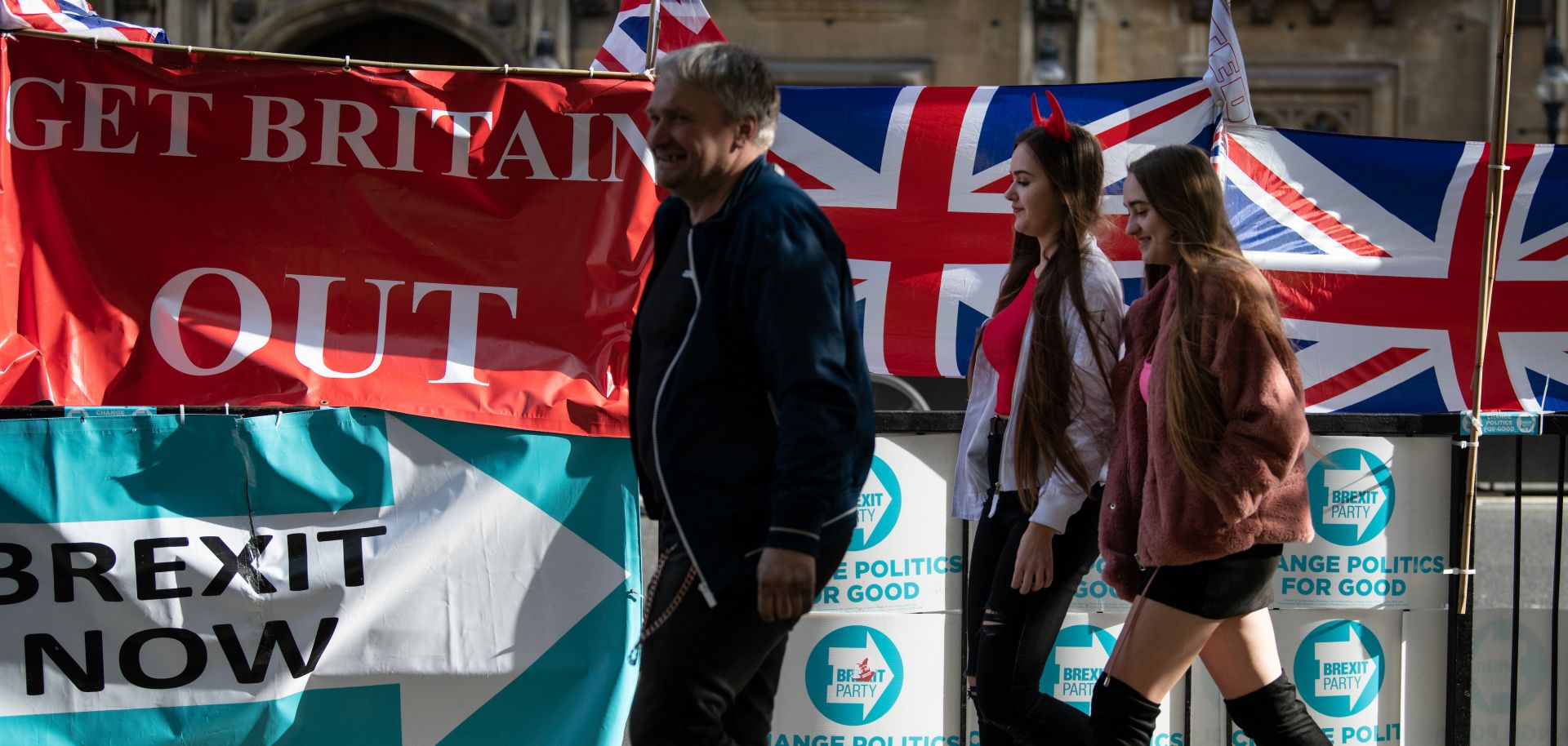 Pedestrians near the British Parliament building pass banners touting Brexit.