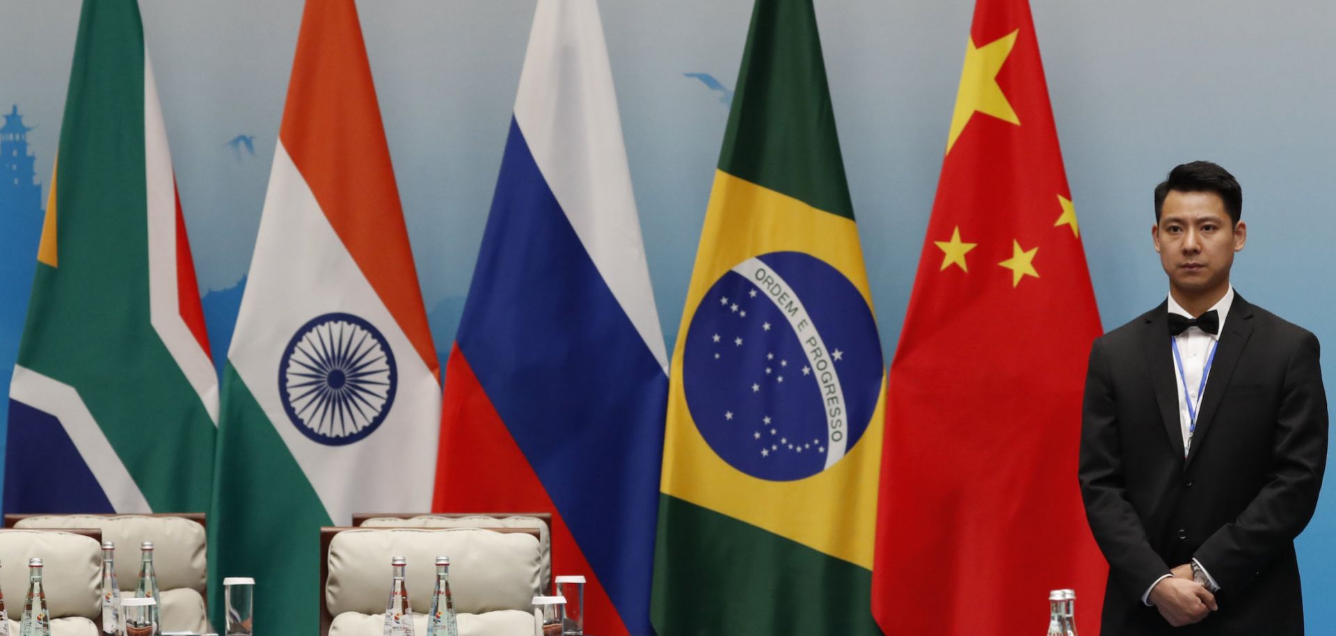 An attendant stands next to South African, Indian, Russian, Brazilian and Chinese flags during a BRICS summit in Xiamen, China, on Sept. 4, 2017. 