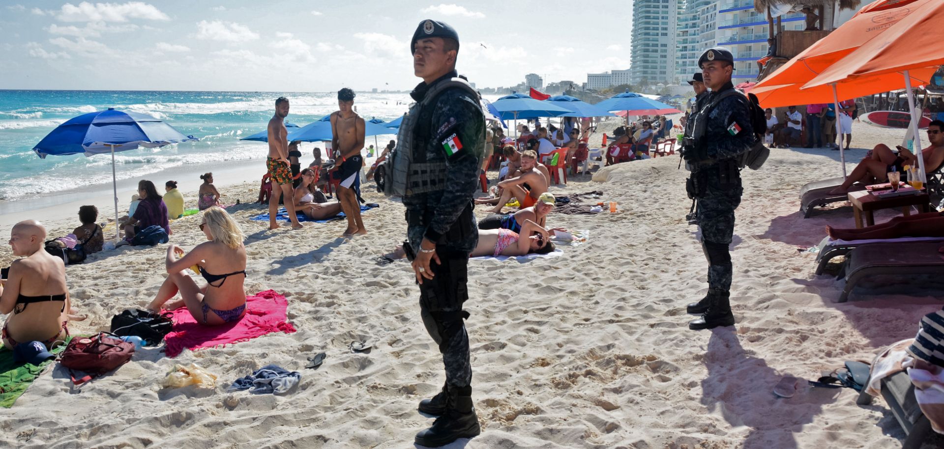 Mexican federal police patrol the beach in Cancun, a resort town rarely touched by violence. But recent drug cartel battle there have resulted in spillover violence that left some tourists dead.