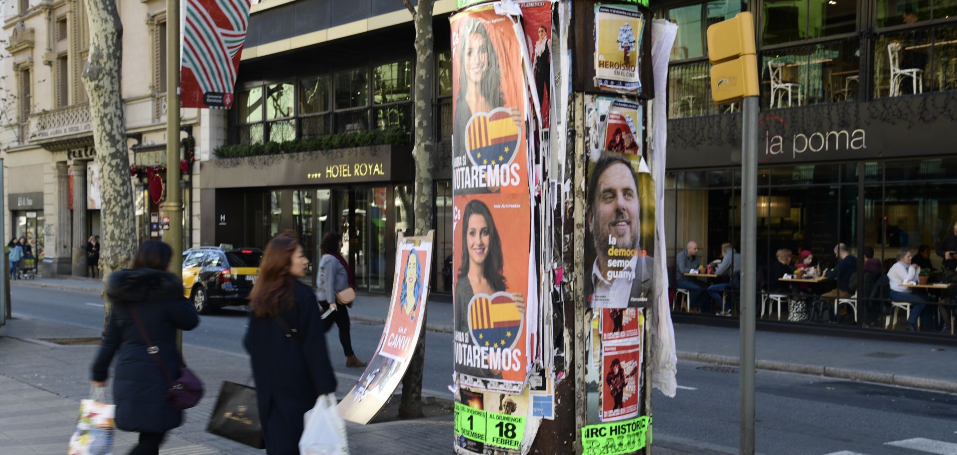 People in Barcelona walk past posters for various parties in the upcoming regional elections. 