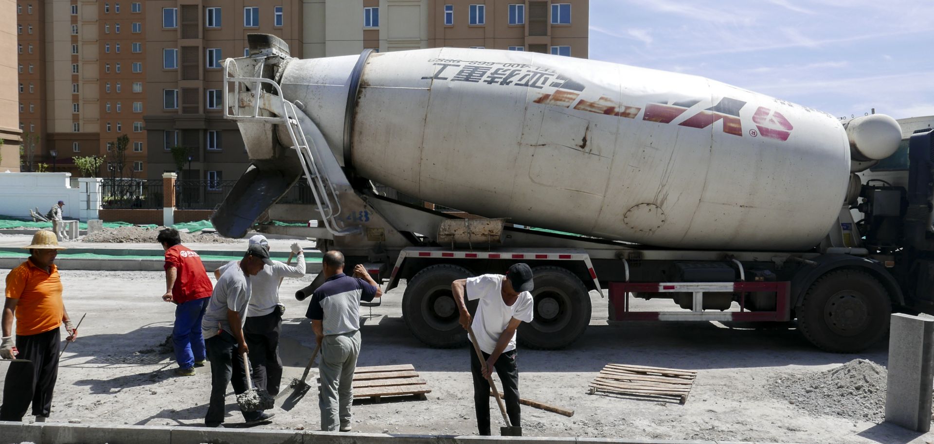 A cement tank car and workers are working on a construction site of a new residential district.