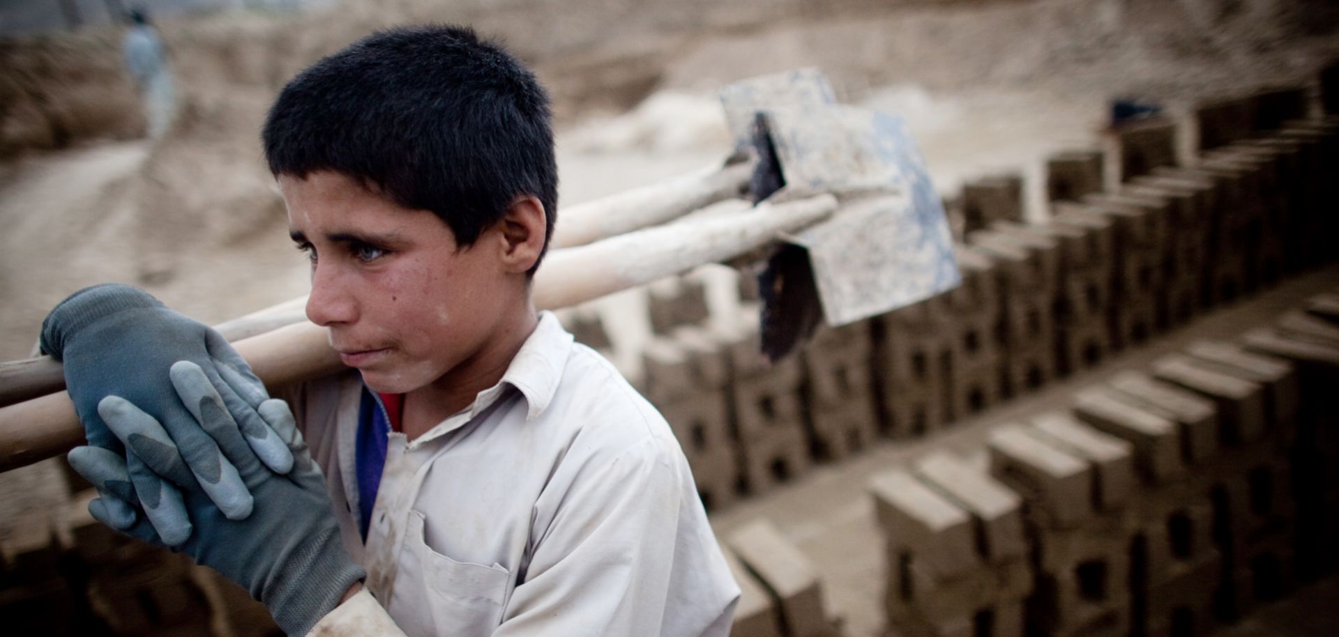 An Afghan child carries shovels at a brick factory in Kabul. The percentage of the world's population in slavery may be at its lowest point in history, but in absolute terms, the global number of enslaved people is higher than it's ever been.