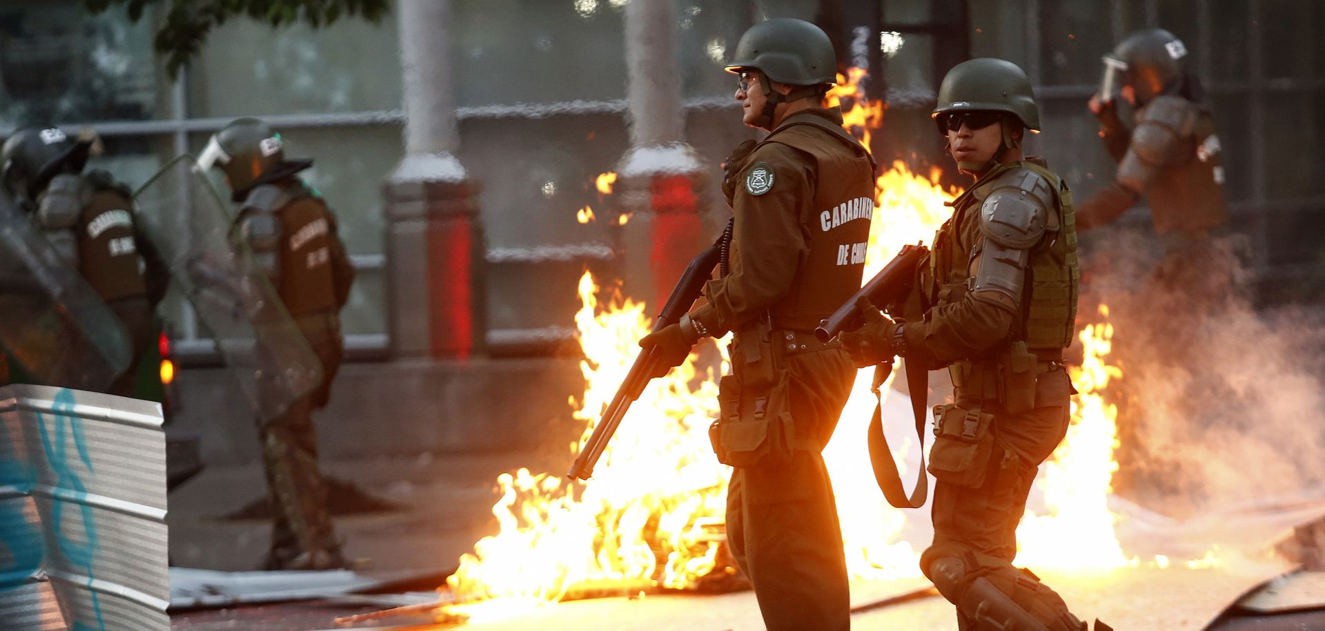 Riot police officers stand guard in front of a burning barricade during a protest against the government of President Sebastian Pinera on Nov. 7, 2019, in Santiago, Chile. 