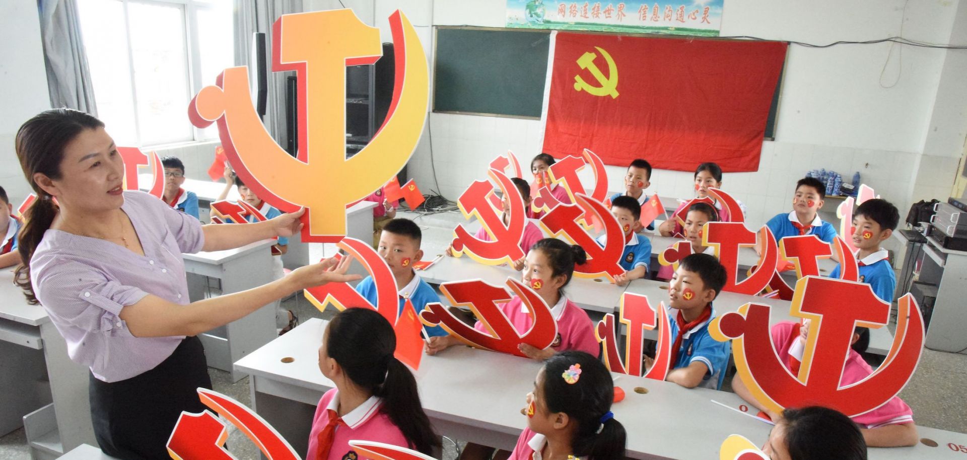 A teacher and her students hold Chinese Communist Party emblems during a lesson about the party’s history in Lianyungang, China, on June 28, 2020. 