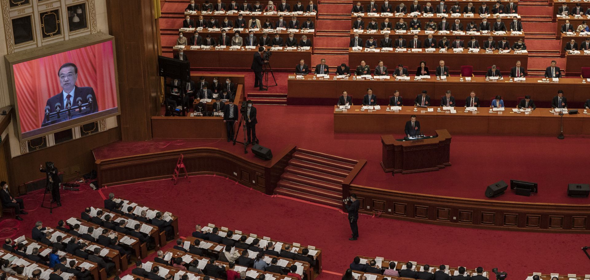 Chinese Premier Li Keqiang speaks on a podium and is seen on a large screen at the opening session of the National People's Congress at the Great Hall of the People on March 5, 2022, in Beijing.