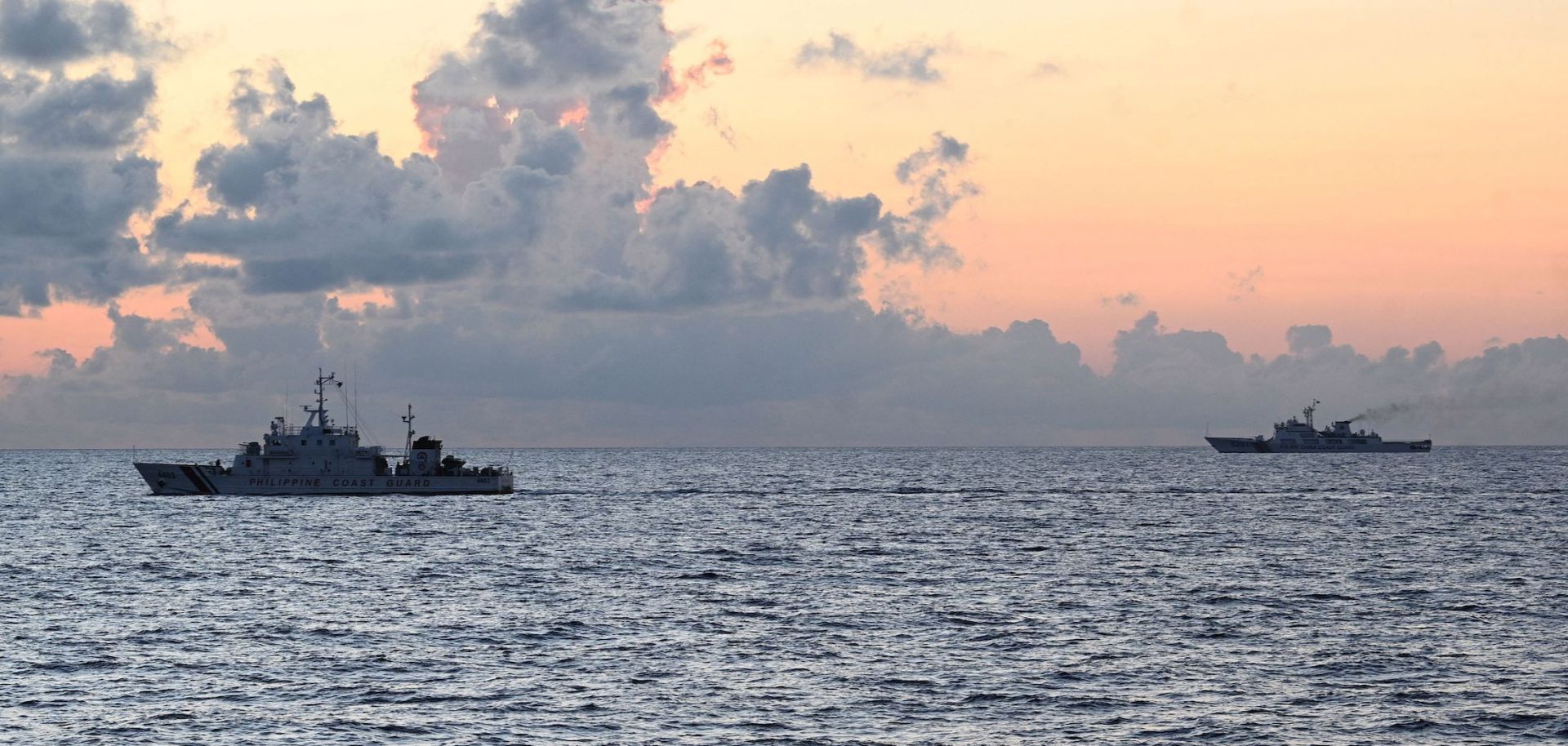 A Chinese coast guard ship (R) shadows the Philippine coast guard vessel BRP Malapascua (L) while on patrol at the Second Thomas Shoal in the Spratly Islands in the disputed South China Sea on April 23, 2023.