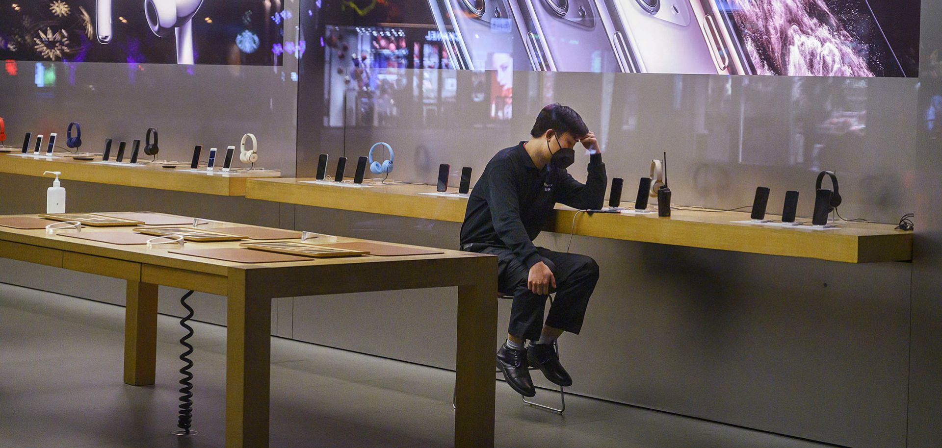 An employee sits in the showroom of an Apple store in Beijing after it closed for the day on Feb. 1, 2020.