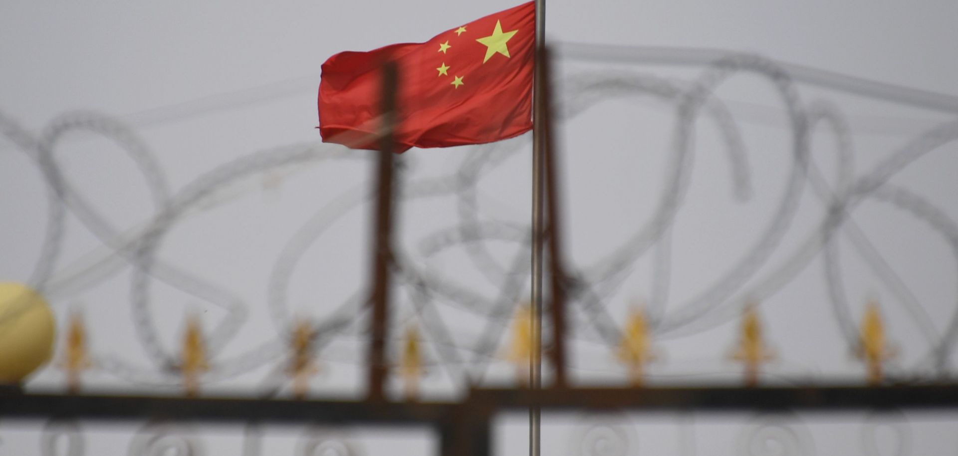 The Chinese flag behind razor wire.