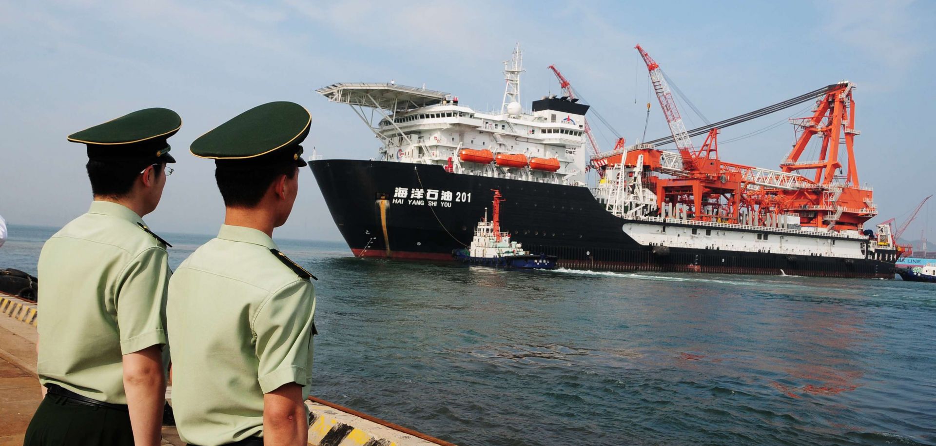 Two Chinese paramilitary guards watch as China National Offshore Oil Corp. (CNOOC)'s first independent deep-water oil drilling rig, leaves the port of Qingdao.
