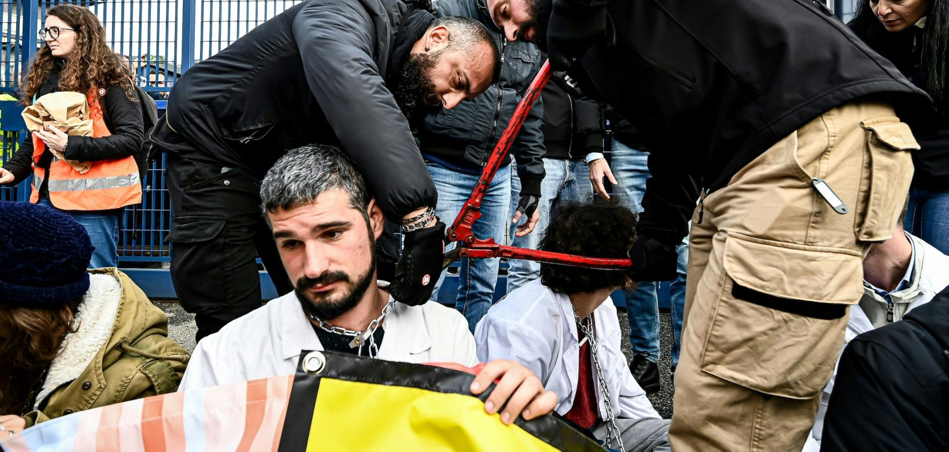 Police officers remove a chain Nov. 10, 2022, from the neck of an activist as climate activists block the entrance of the Milano Linate Prime fixed-base operator airport facility in Milan.