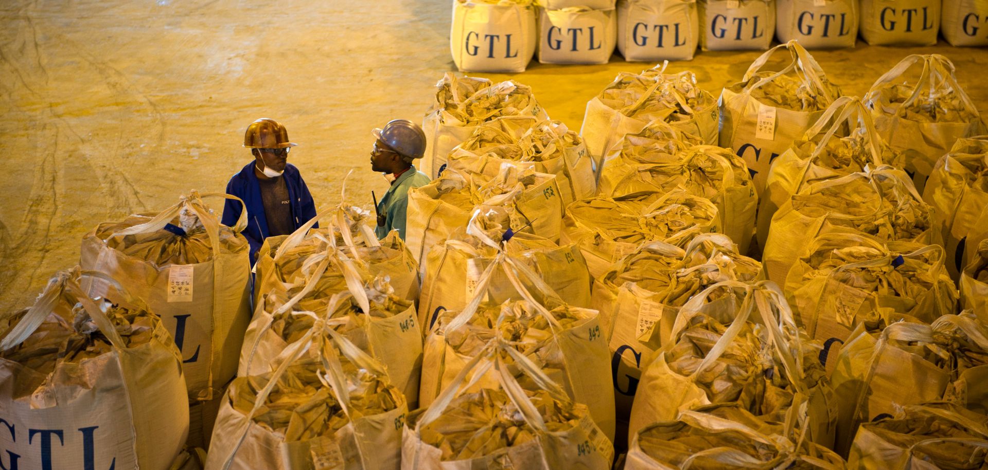 Congolese workers stand beside bags of a mixture of cobalt and copper.