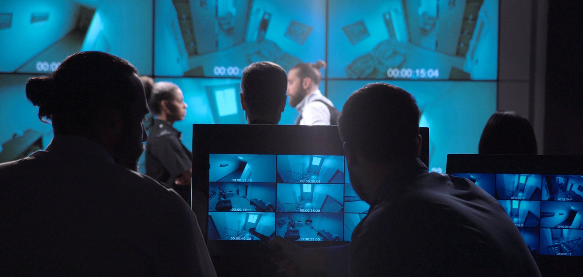 A corporate surveillance team examines security footage of an office entrance.