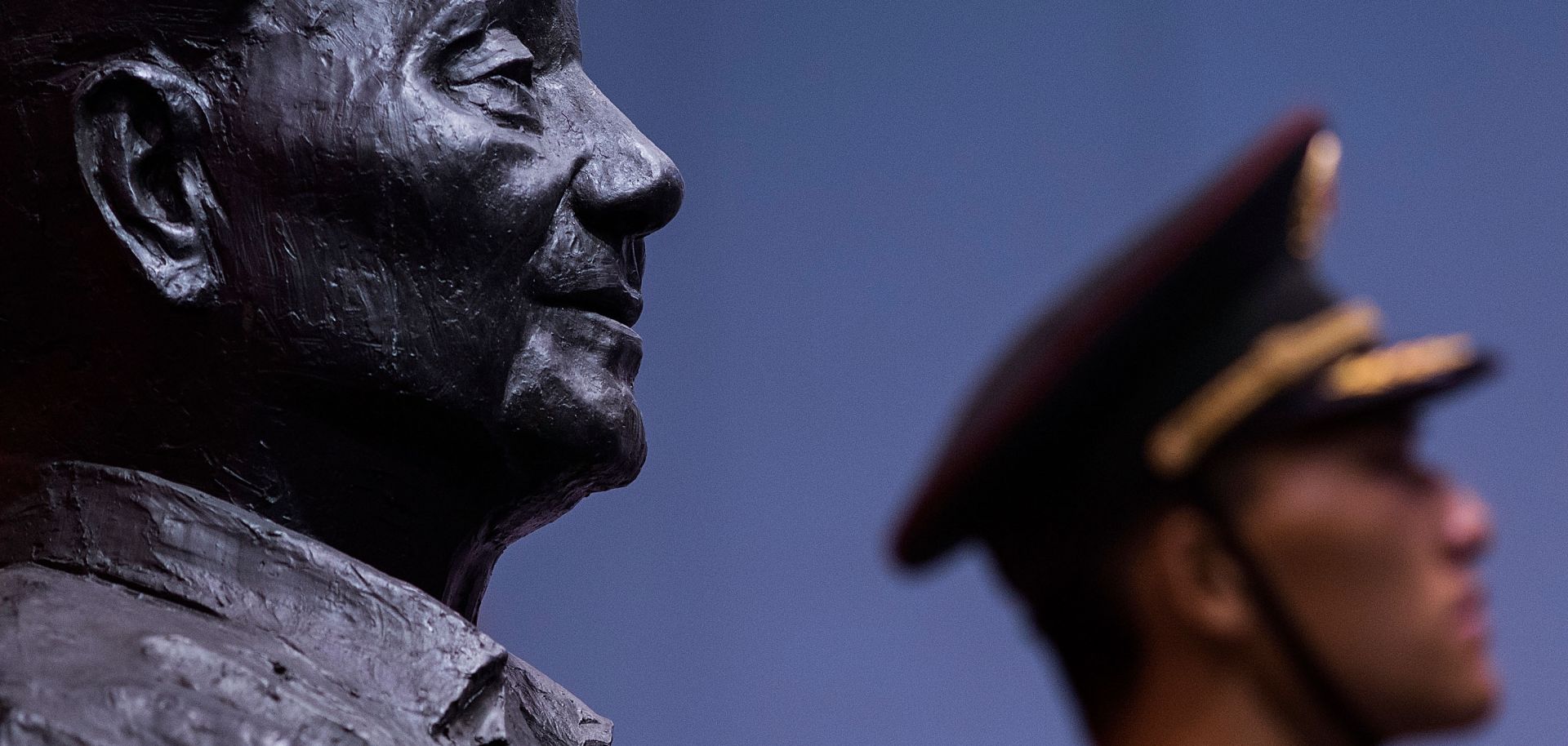A bust of former Chinese leader Deng Xiaoping looks out at a member of China's People's Liberation Army.