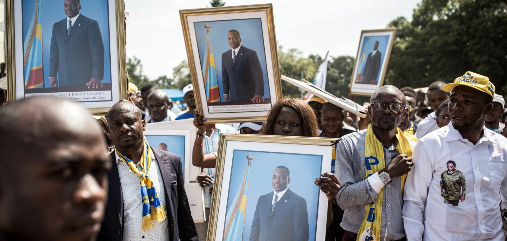 People hold up portraits of the Democratic Republic of the Congo’s former president, Joseph Kabila, as they arrive to attend newly elected President Felix Tshisekedi's inauguration on Jan. 24, 2018.