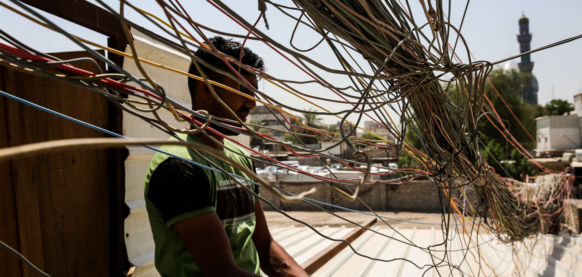 This photo shows an Iraqi man checking a mass of wires connecting homes in Baghdad to electricity.