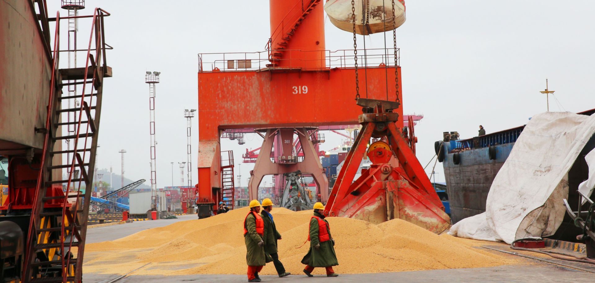 Chinese workers walk past imported soybeans at a port in Nantong, Jiangsu province, on April 4, 2018.