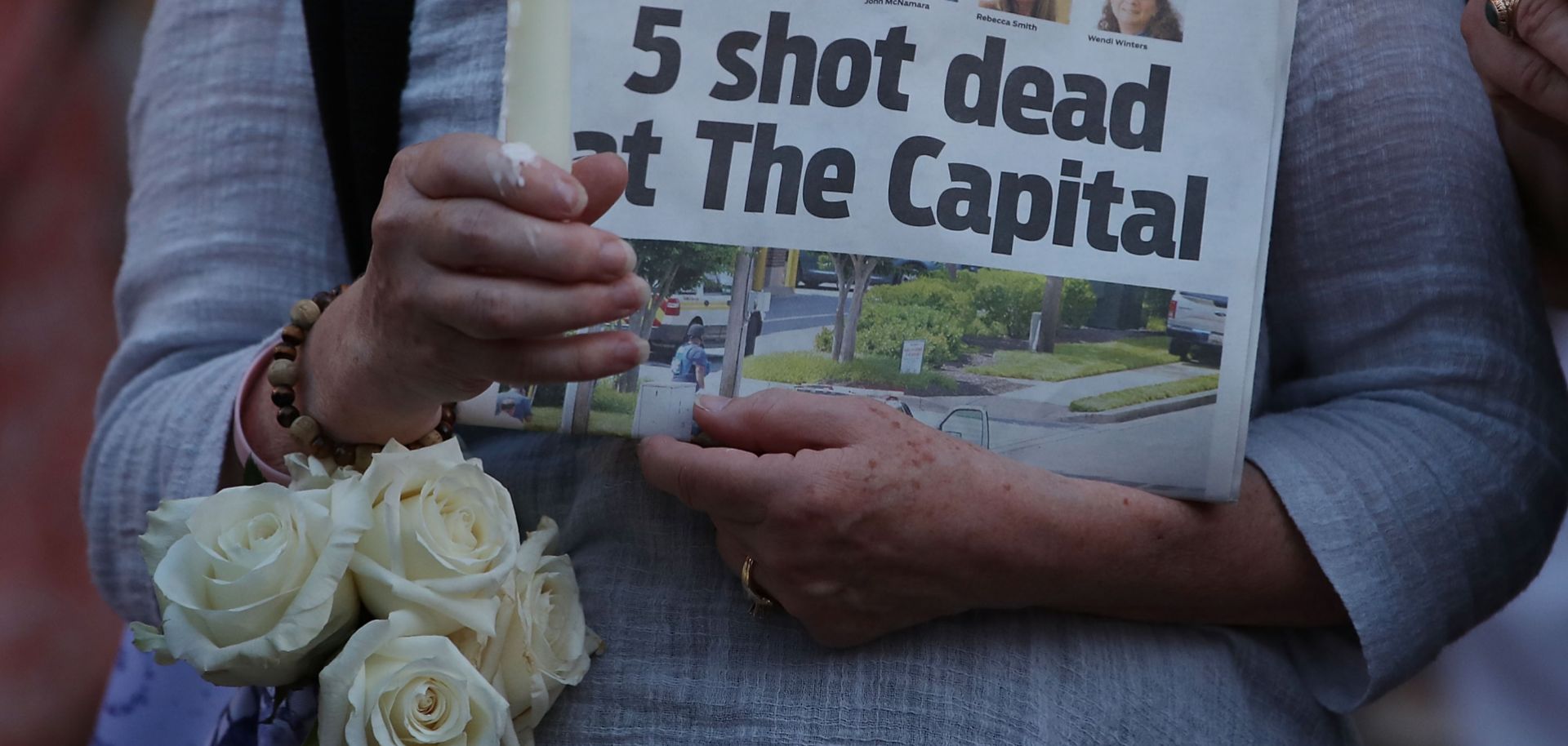 A woman holds a copy of the Capital Gazette newspaper during a candlelight vigil to honor the five people who were killed on June 28, 2018.