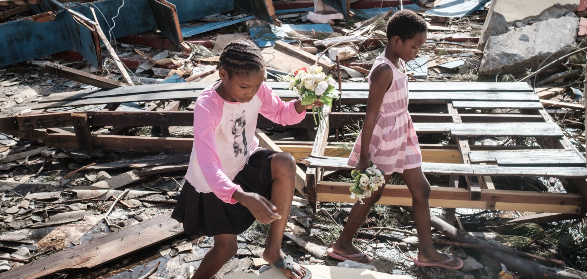 Girls collect artificial flowers from the rubble of a building destroyed by Cyclone Idai at Sacred Heart Catholic Church in Beira, Mozambique, on March 24, 2019.