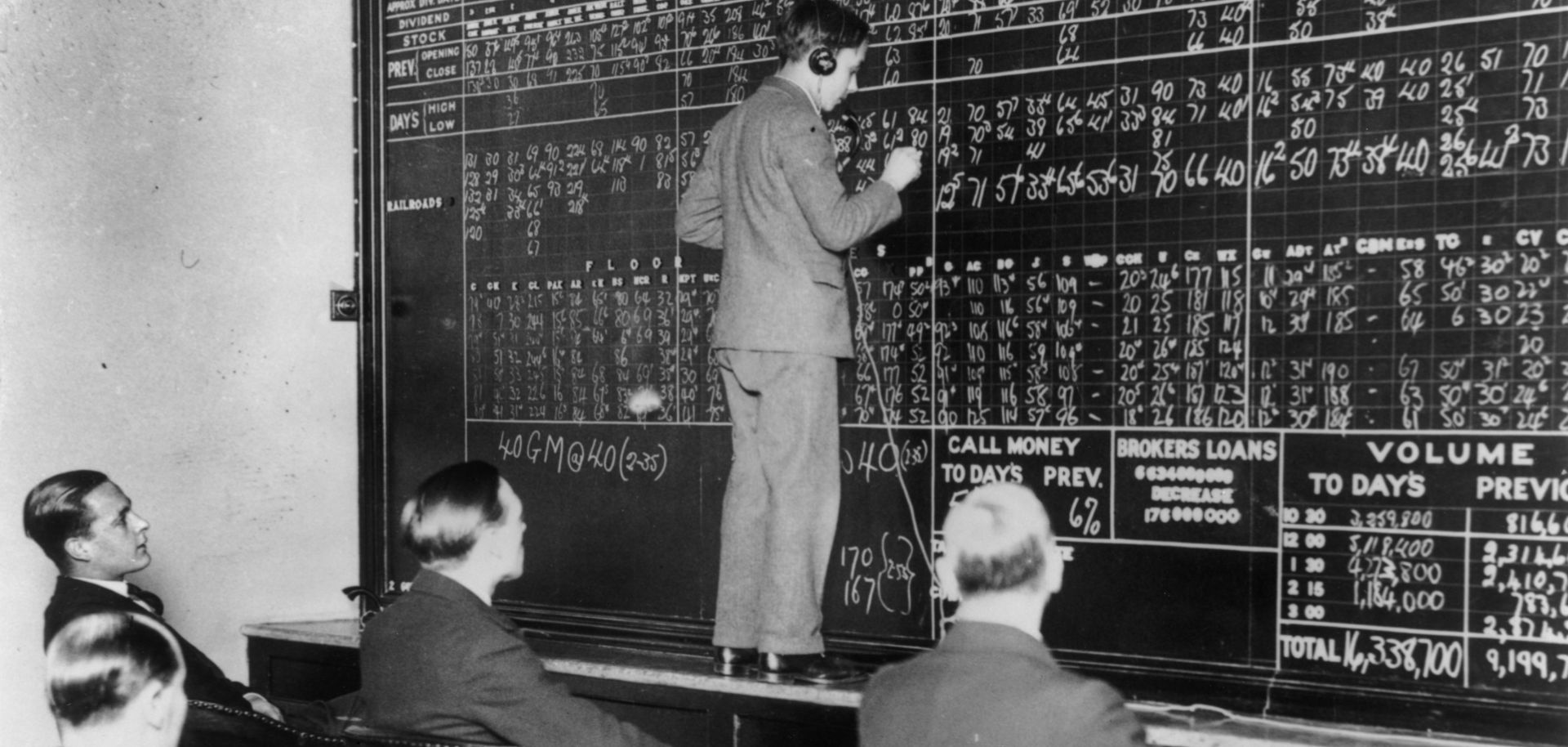 A telephone operator in London records the changes in New York's crashing stock market in 1929 as a few men look on with interest.