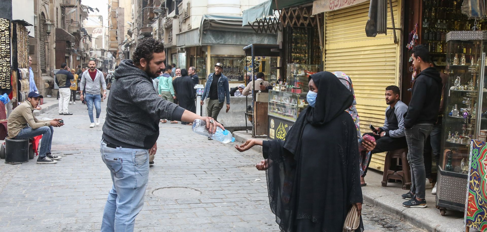 A man provides a pedestrian with hand sanitizer as protection against COVID-19 on the historic Al-Moez street in Cairo, Egypt, on March 23, 2020.