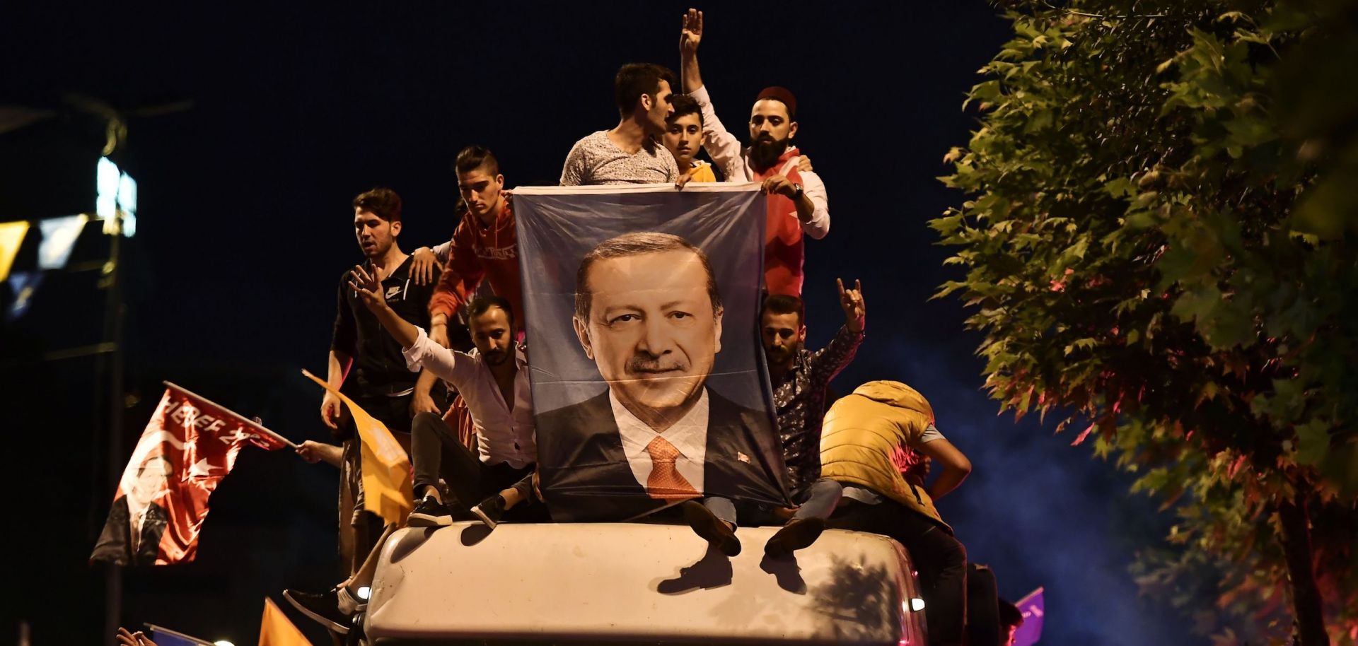 In this photograph, Turks celebrate with a poster of President Recep Tayyip Erdogan outside his party headquarters in Istanbul on June 24, 2018.