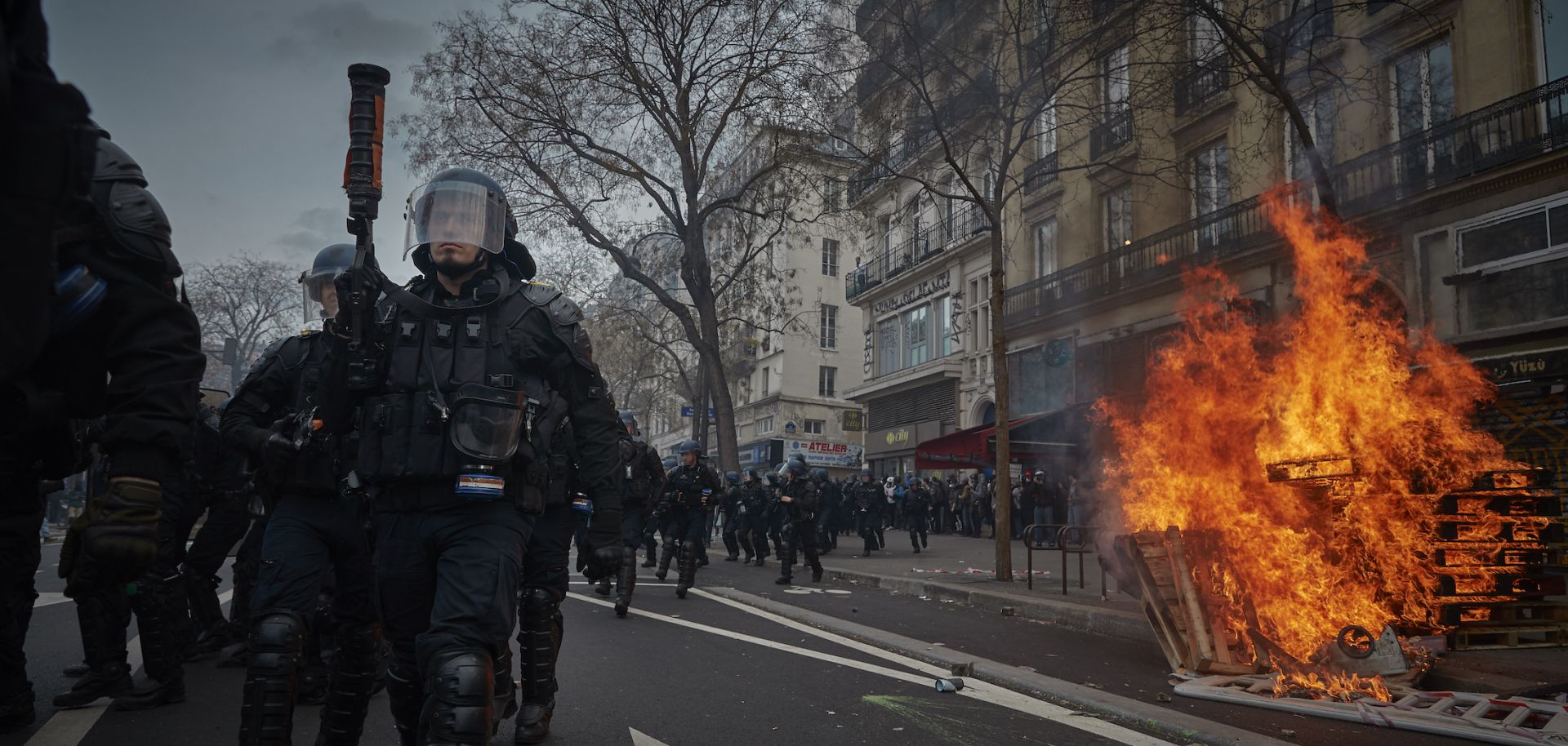 Riot police walk past a street fire during violent clashes over the government's reform of the pension system March 23, 2023, in Paris.