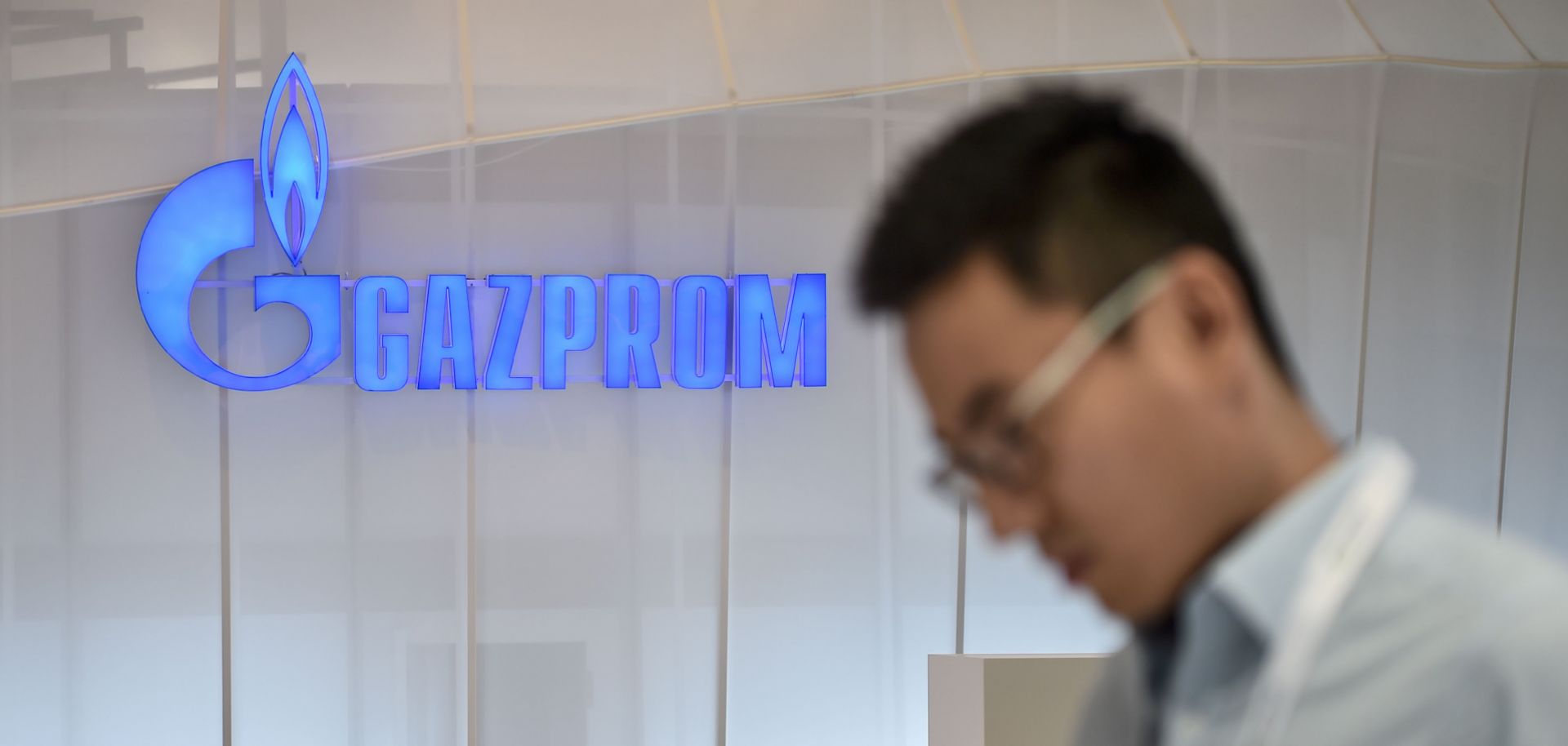 A man looks at his mobile phone as he walks past a Russian Gazprom stand in Istanbul.