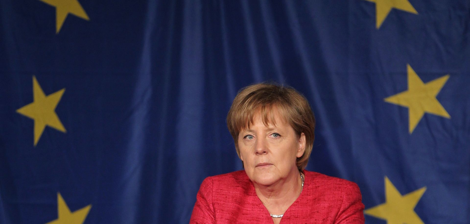 German Chancellor Angela Merkel sits in front of a flag of the European Union.