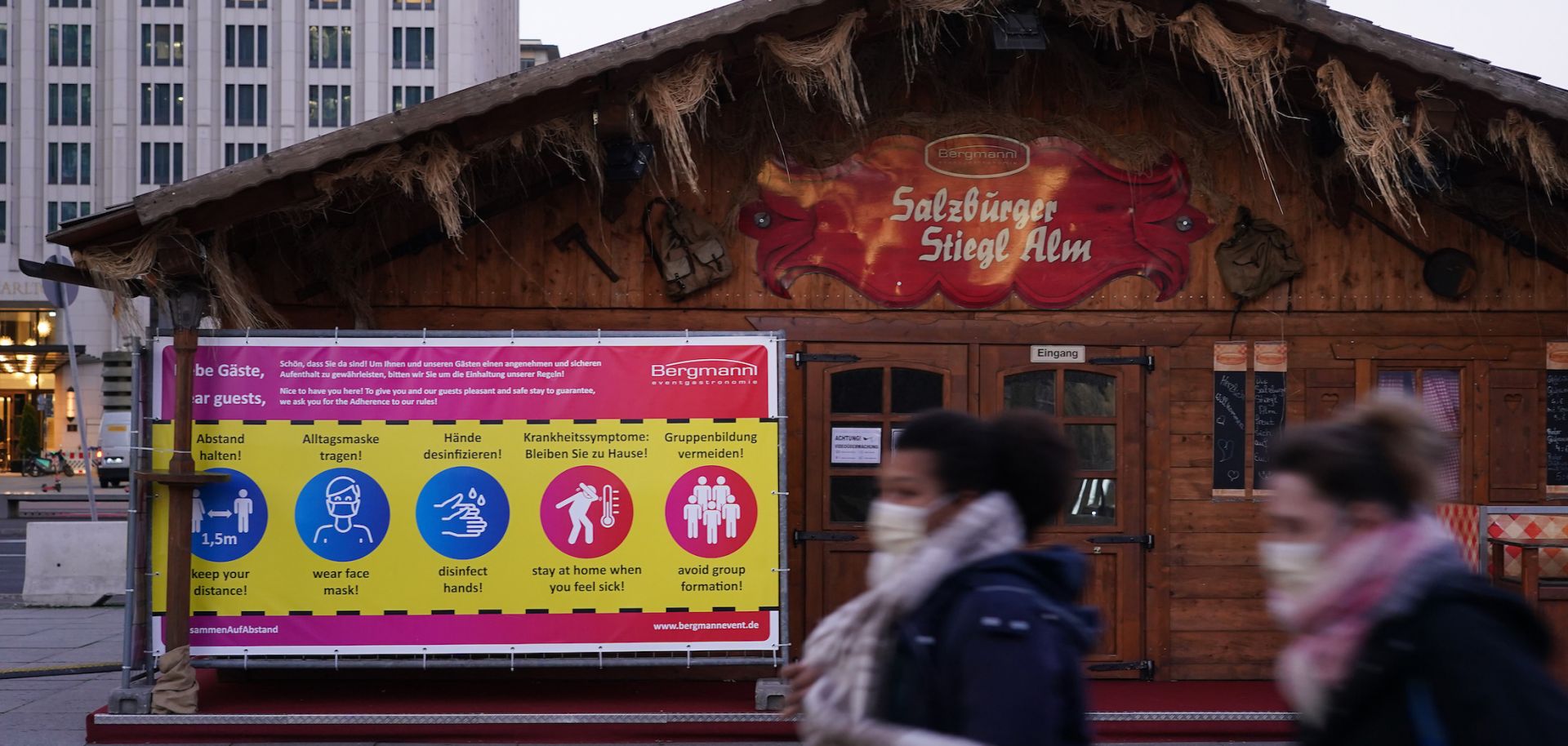 People wearing face masks walk past Christmas market stalls on Nov. 20, 2020, at Potsdamer Platz in Berlin, Germany.