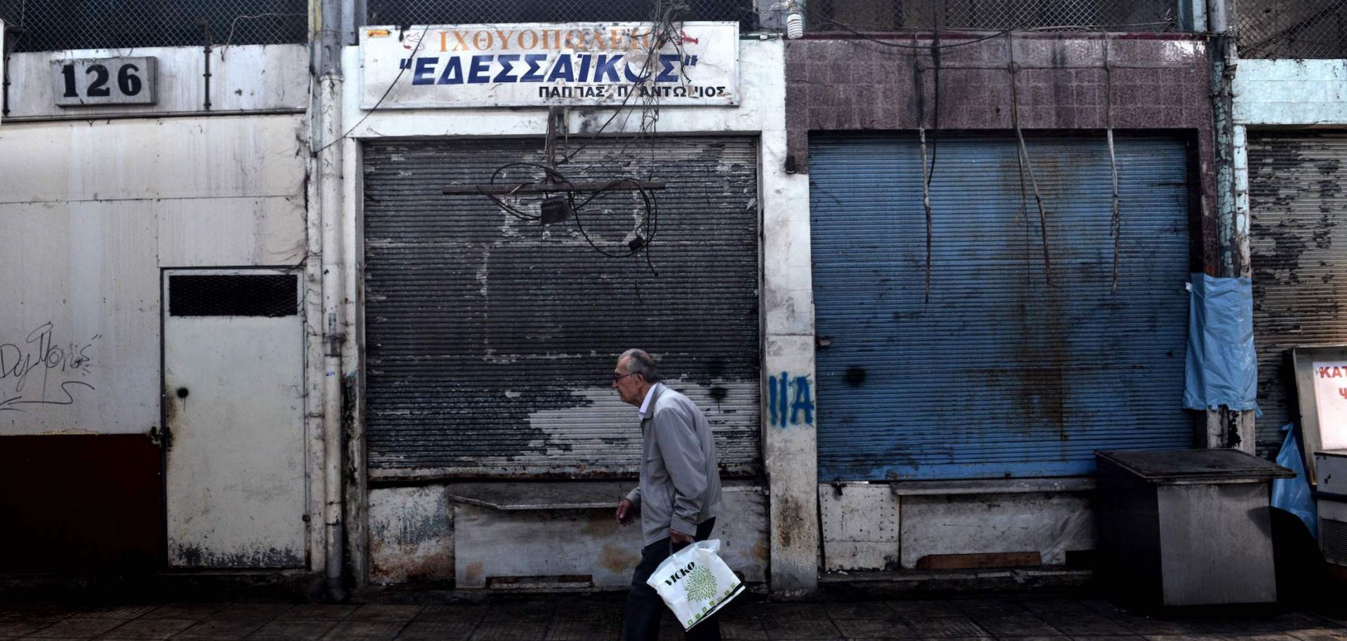 A man walks past closed shops in the center of the Greek city of Thessaloniki on June 21, 2018. 