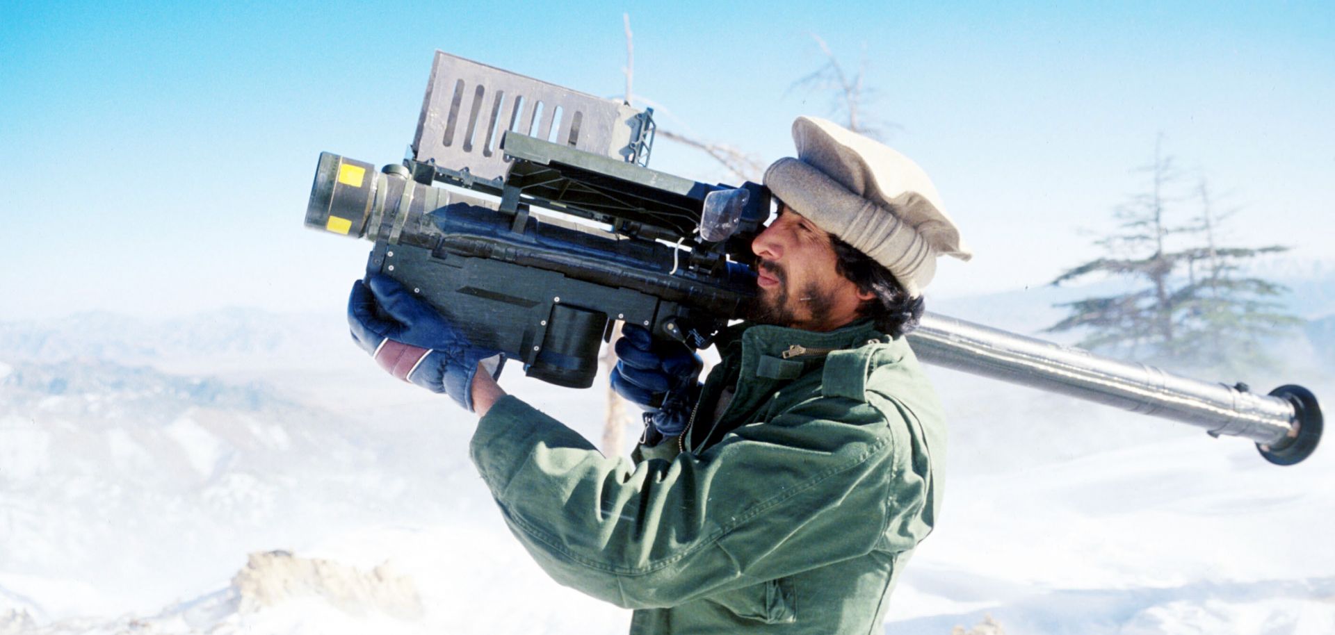 A man points a stinger missile into the air on a snowy mountain.