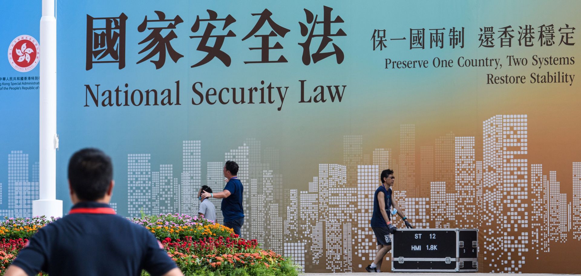 Technicians in Hong Kong walk next to a banner supporting China’s new national security law following a flag-raising ceremony marking the 23rd anniversary of the city’s British handover on July 1, 2020. 