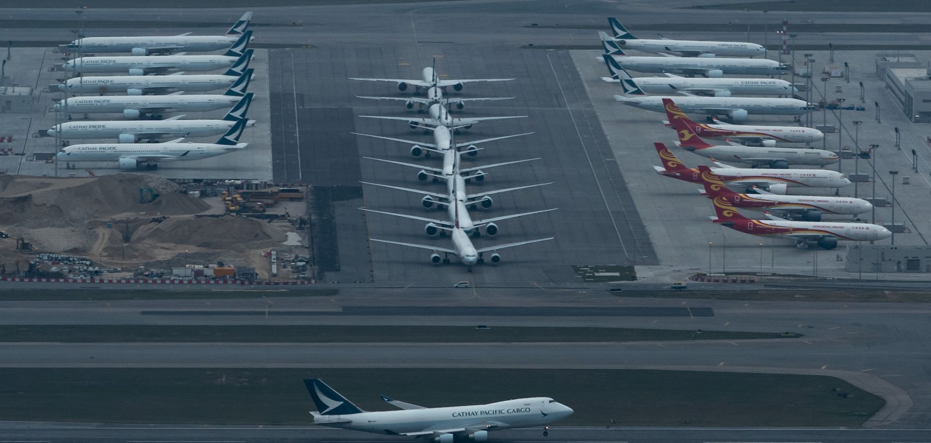 A Cathay Pacific aircraft takes off on a runway as others park at Hong Kong International Airport on March 6, 2020.