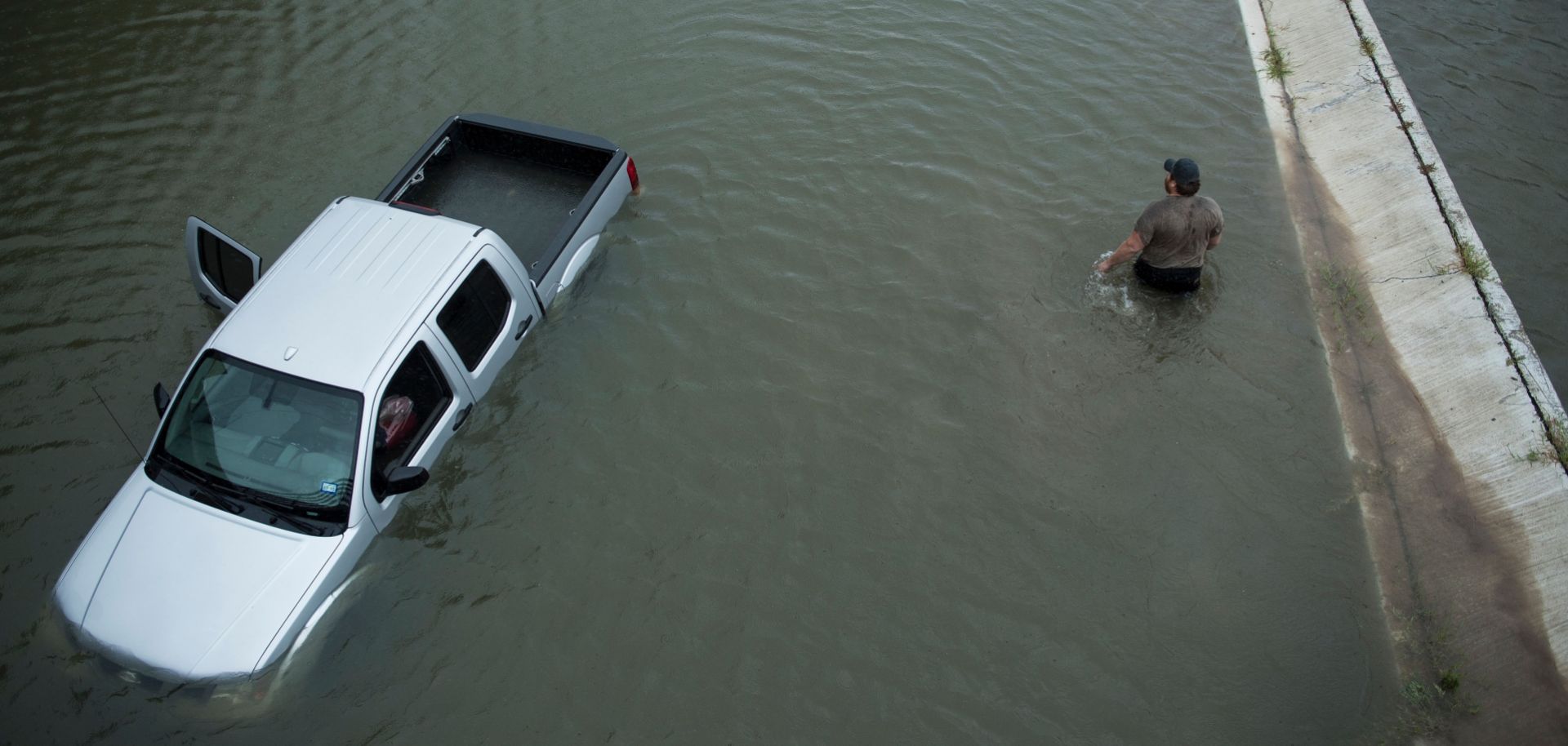 A driver walks past an abandoned truck while checking the depth of an underpass in the aftermath of Hurricane Harvey in Houston, Texas.