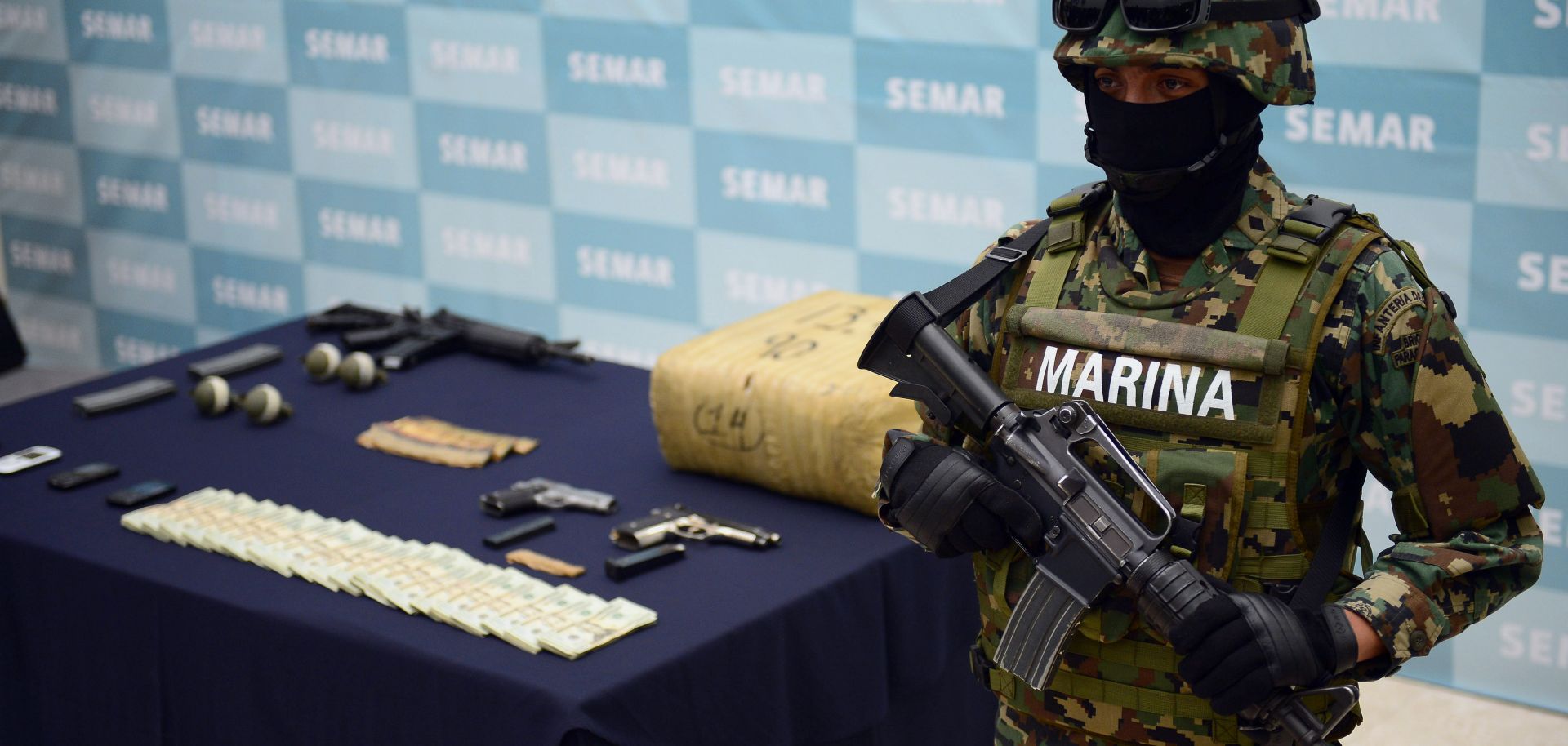 A soldier guards firearms, hand grenades and other illegal items seized from the Zeta drug cartel.