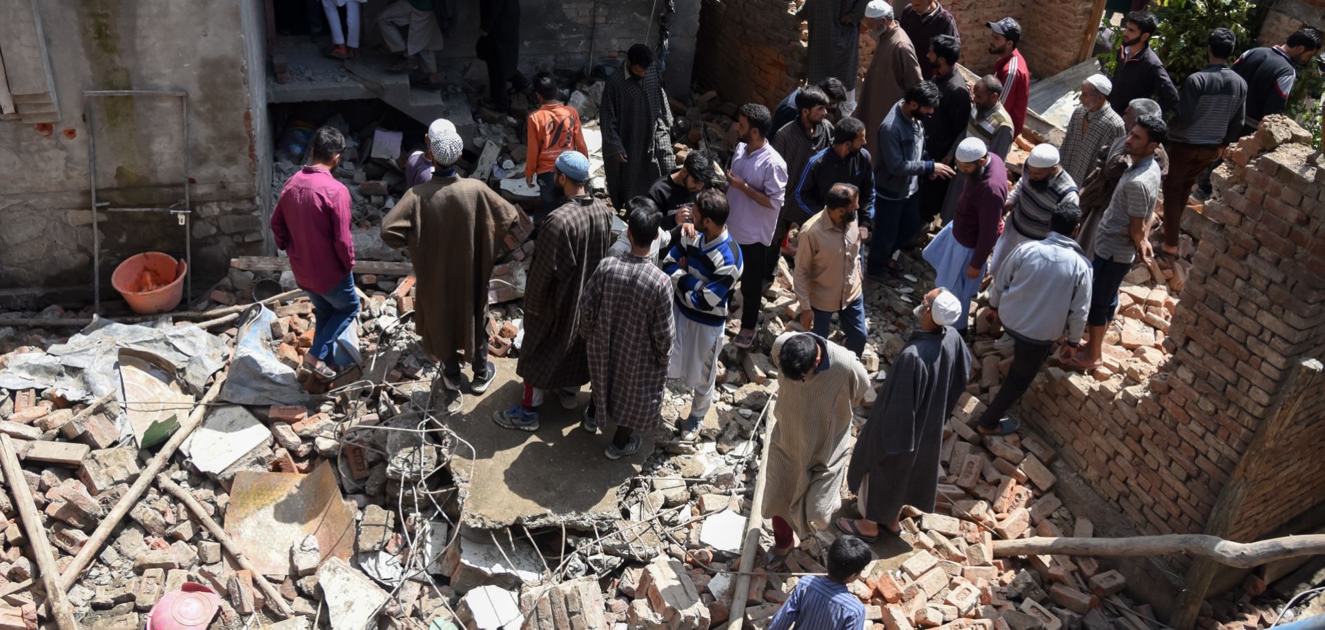 Kashmiri villagers gather around a partially damaged house after a gunfight in Pulwama, South of Srinagar, on May 18, 2019, after four rebels died in two separate clashes.