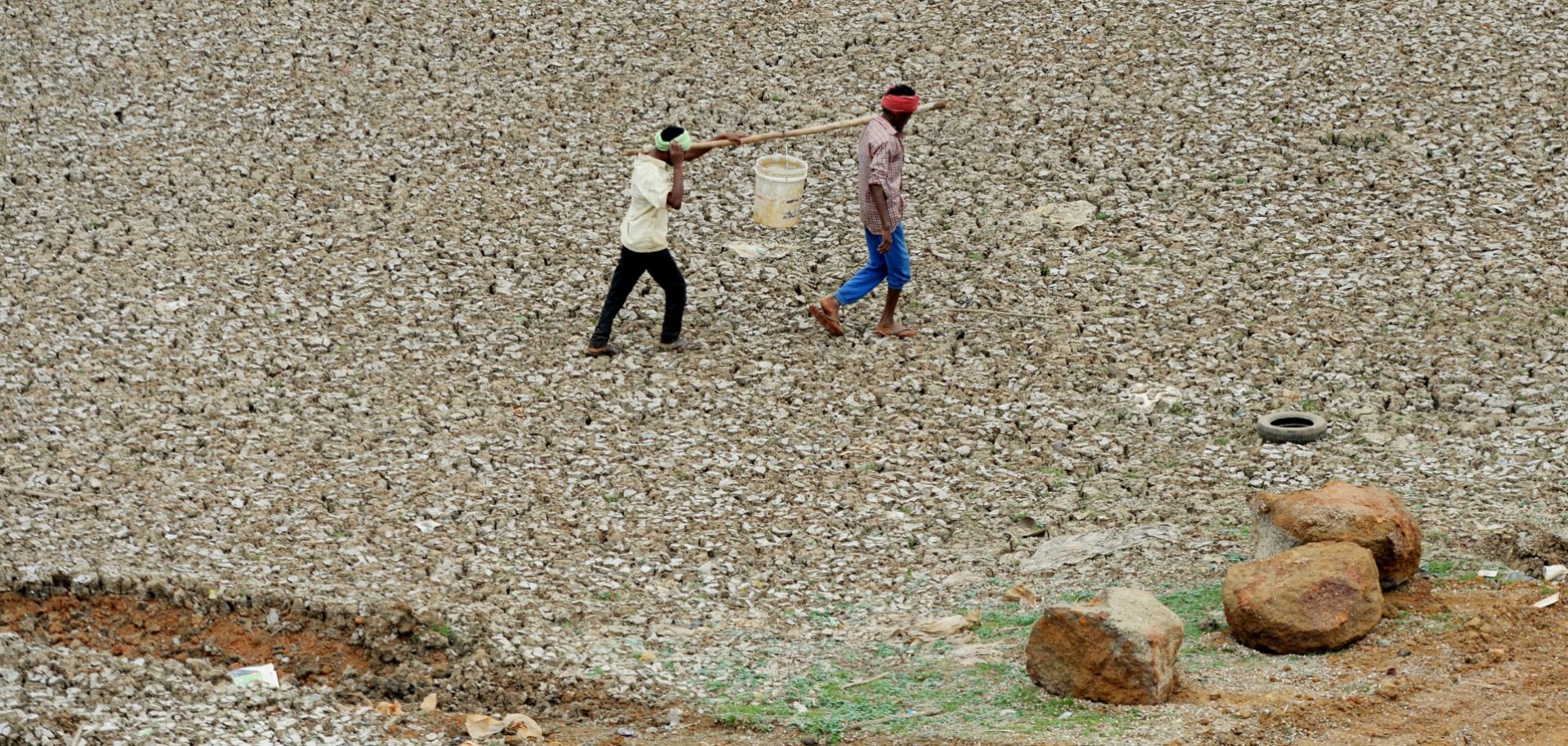 Workers carry water collected from Puzhal lake on June 20, 2019. Puzhal is one of four main reservoirs that supply the southern Indian city of Chennai with water; all are running dry.