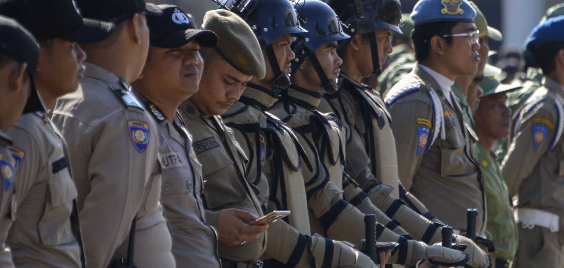 An Indonesian policeman (5th L) checks his mobile phone while standing in line during a security roll call in Banda Aceh on April 11, ahead of the country's general elections.