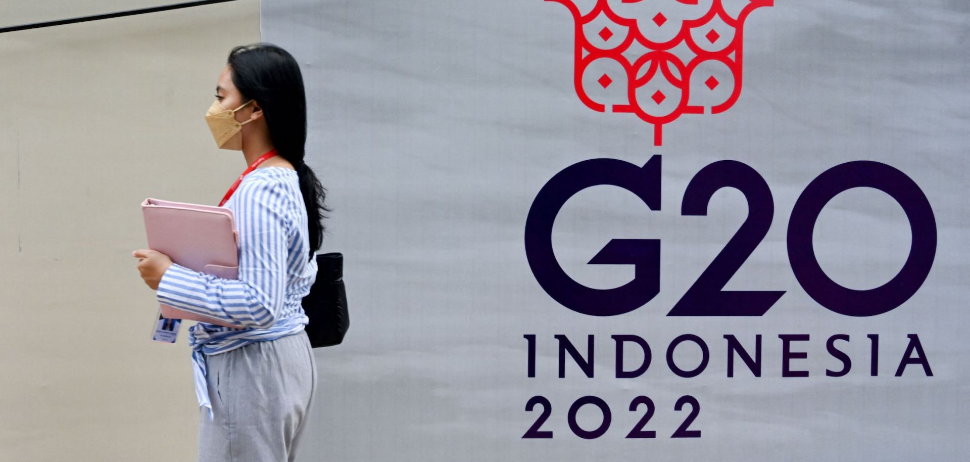 A woman in Jakarta, Indonesia, walks past a logo for the upcoming G-20 Summit in Bali on Nov. 8, 2022. 
